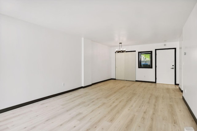 empty room featuring a notable chandelier and light hardwood / wood-style floors