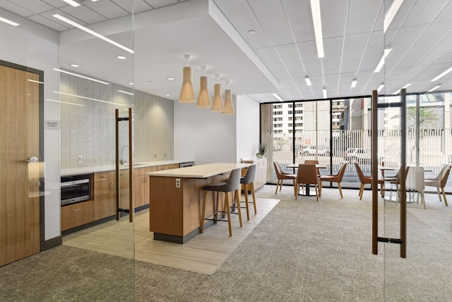 kitchen featuring floor to ceiling windows, a kitchen island, light colored carpet, and wall oven