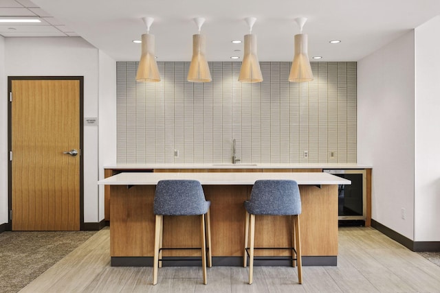 kitchen with wine cooler, a breakfast bar, sink, and a kitchen island