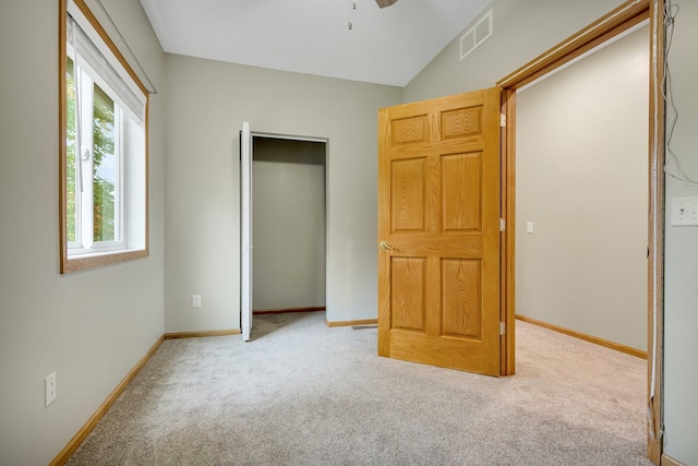 unfurnished bedroom featuring ceiling fan, light colored carpet, lofted ceiling, and a closet