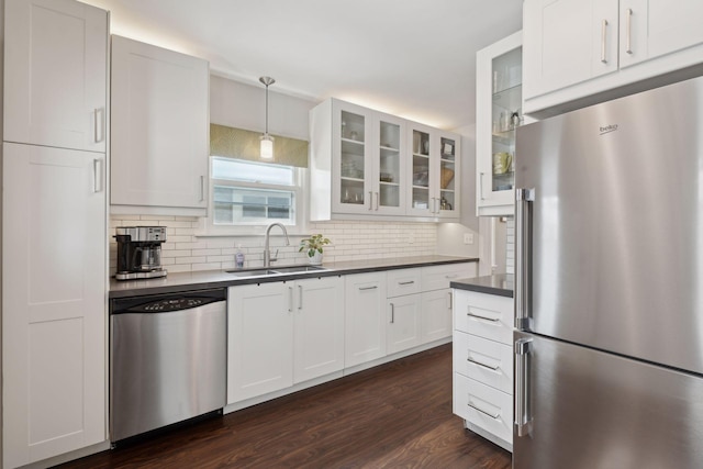 kitchen with stainless steel appliances, white cabinetry, sink, and pendant lighting