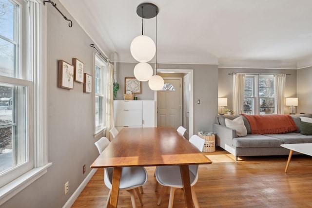 dining area with ornamental molding and light hardwood / wood-style flooring