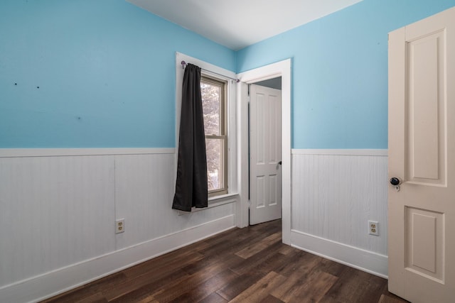 109 3rd St E, Ada, MN 56510 - unfurnished bedroom with a wainscoted wall, dark wood-style floors, baseboards, and wooden walls