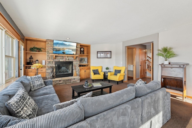 living room featuring a stone fireplace, carpet, and built in features