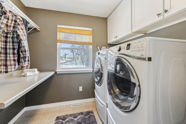 clothes washing area with cabinets and washing machine and dryer