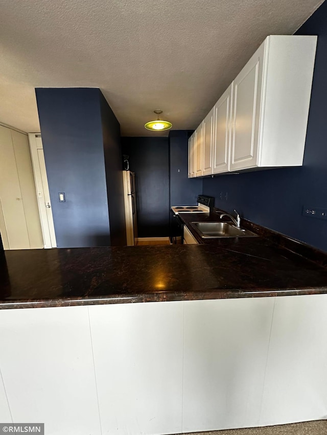 kitchen featuring white cabinetry, sink, and a textured ceiling