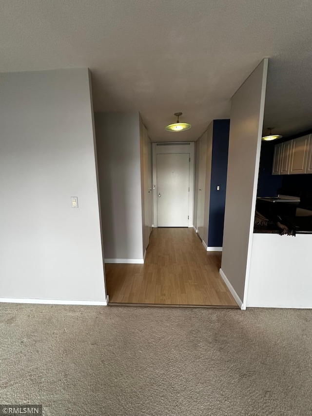 corridor featuring carpet floors, a textured ceiling, and baseboards