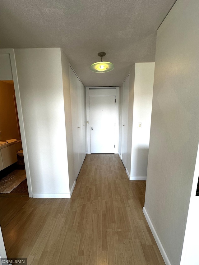 hallway featuring wood finished floors and baseboards
