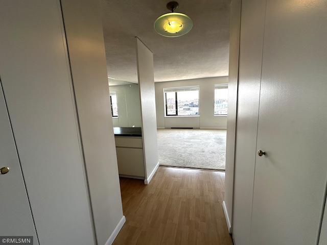 hallway with carpet, wood finished floors, and baseboards