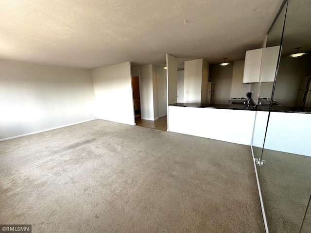 unfurnished living room featuring baseboards, a textured ceiling, and carpet