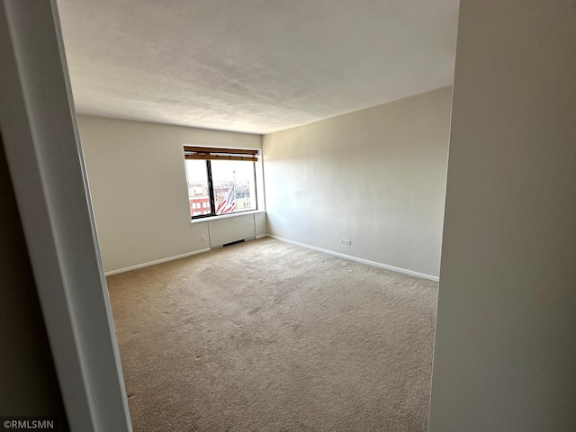 carpeted spare room featuring baseboards