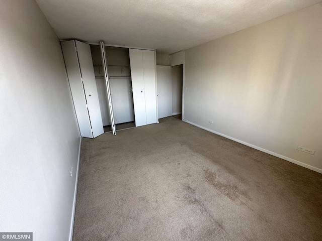 unfurnished bedroom featuring baseboards, a closet, and carpet flooring