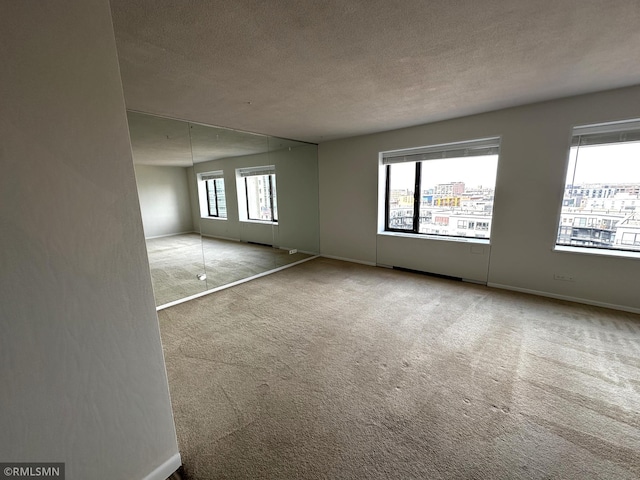 carpeted empty room with baseboards and a textured ceiling