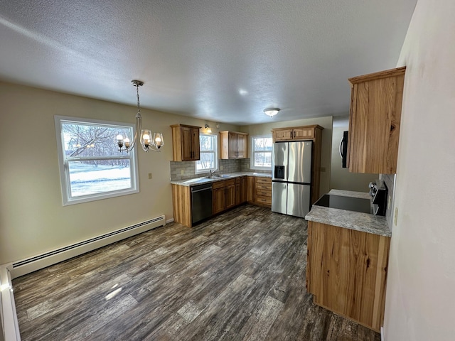 kitchen featuring tasteful backsplash, a baseboard radiator, appliances with stainless steel finishes, brown cabinets, and dark wood-type flooring