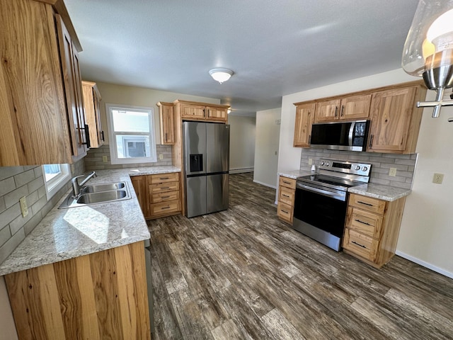 kitchen with dark wood finished floors, baseboards, stainless steel appliances, and a sink