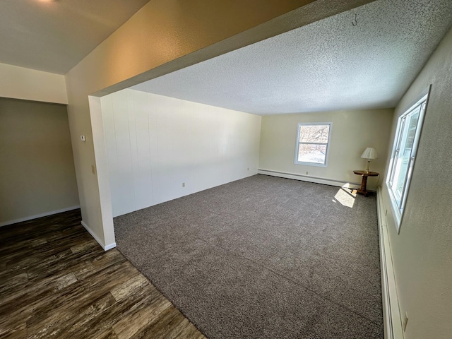 unfurnished room featuring a textured ceiling, a textured wall, a baseboard heating unit, dark wood-style floors, and dark carpet