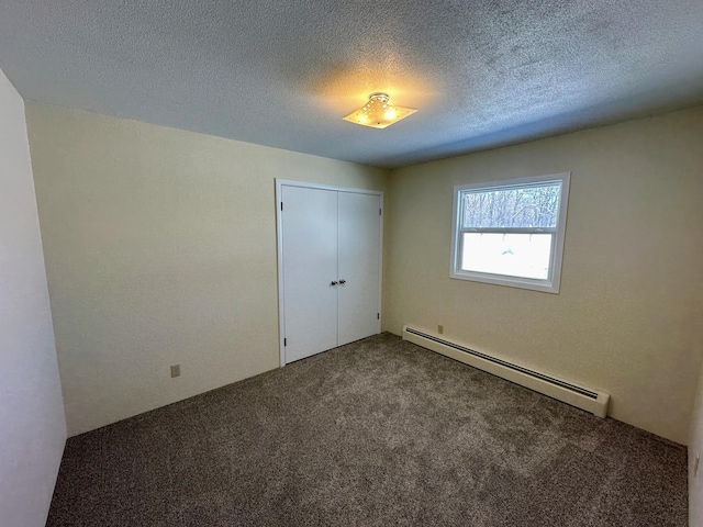 unfurnished bedroom with carpet, a closet, a textured ceiling, and baseboard heating