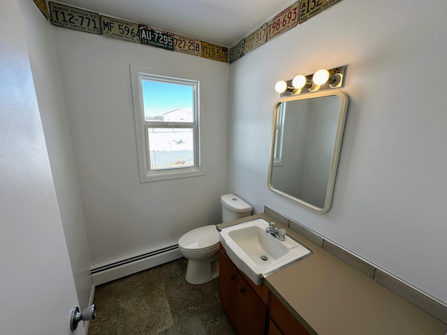 bathroom with a baseboard heating unit, stone finish flooring, toilet, and vanity