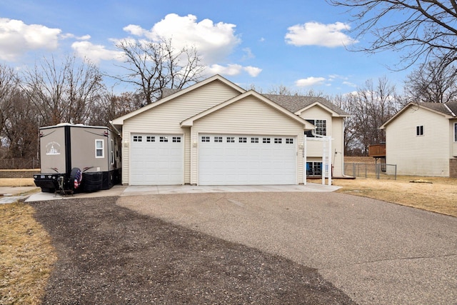 view of front facade with a garage, driveway, and fence