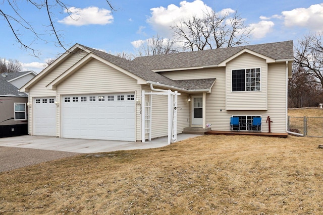 split level home featuring an attached garage, fence, a front lawn, and roof with shingles