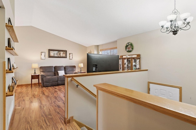 hall with baseboards, wood finished floors, vaulted ceiling, an upstairs landing, and a chandelier