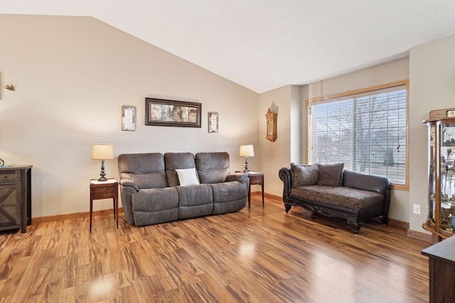 living area with light wood-style floors, vaulted ceiling, and baseboards