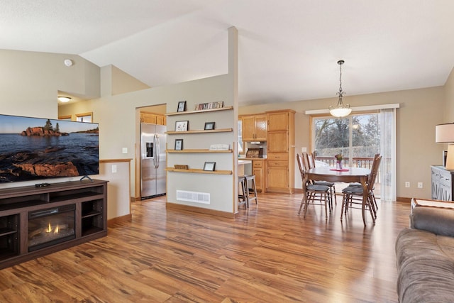 living area with vaulted ceiling, baseboards, visible vents, and light wood-style floors