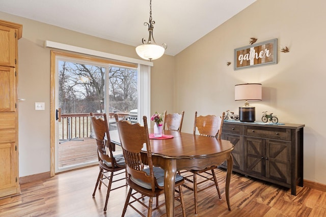 dining area with vaulted ceiling, baseboards, and light wood-style floors