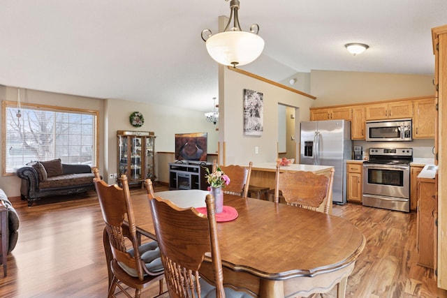 dining space with vaulted ceiling and light wood-style flooring