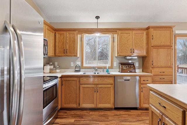 kitchen featuring appliances with stainless steel finishes, light countertops, a sink, and wood finished floors