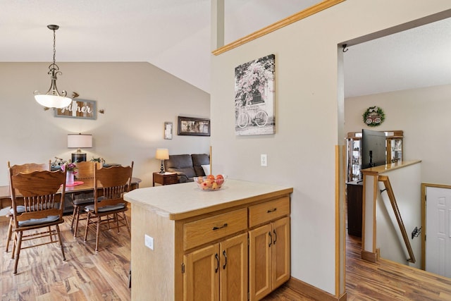 kitchen with lofted ceiling, light countertops, hanging light fixtures, open floor plan, and light wood-type flooring