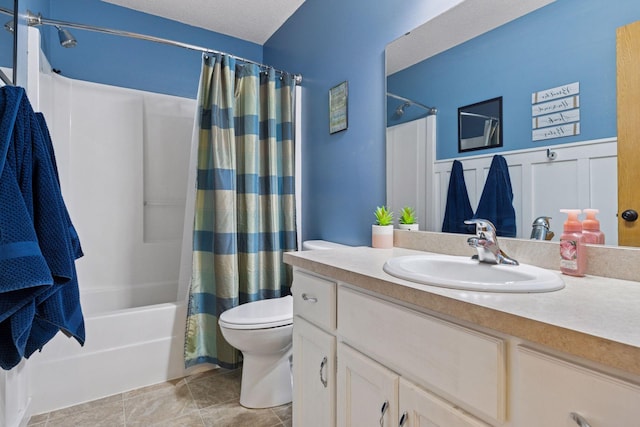 full bath featuring a textured ceiling, toilet, a wainscoted wall, vanity, and shower / bath combo