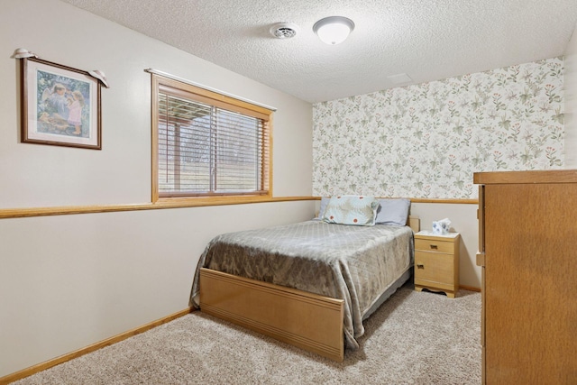 bedroom featuring carpet, visible vents, a textured ceiling, baseboards, and wallpapered walls