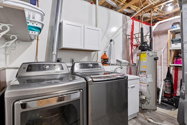 laundry room with independent washer and dryer, light wood-type flooring, gas water heater, and cabinet space