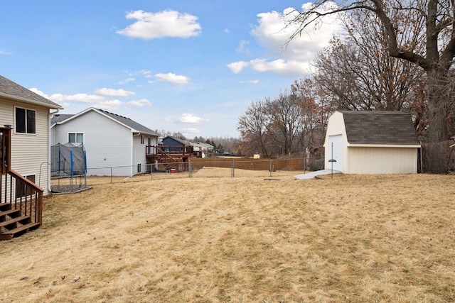 view of yard featuring an outbuilding, a storage shed, a trampoline, and a fenced backyard