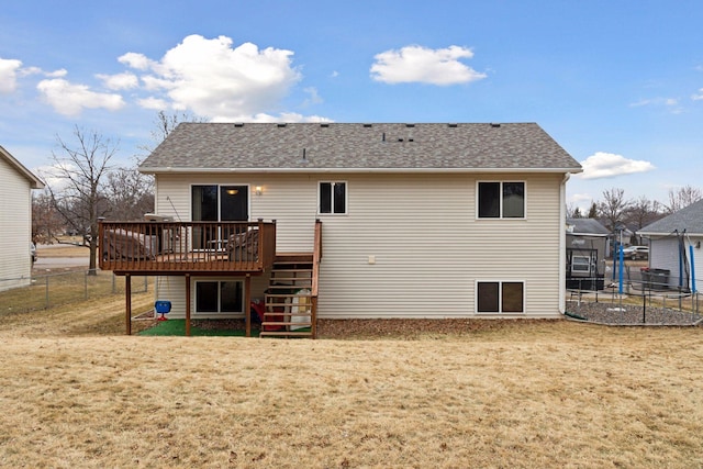 back of house with a lawn, stairs, a trampoline, fence, and a deck