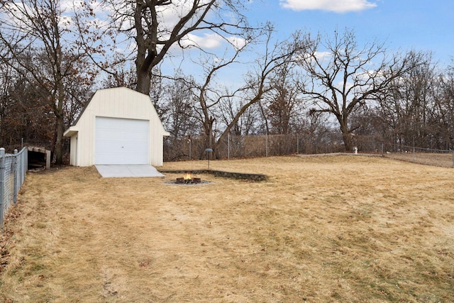 view of yard with a garage, fence, a fire pit, and an outbuilding