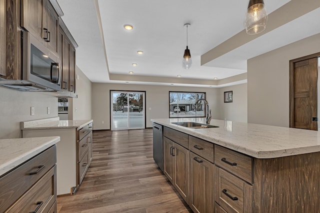 kitchen featuring an island with sink, appliances with stainless steel finishes, sink, and decorative light fixtures