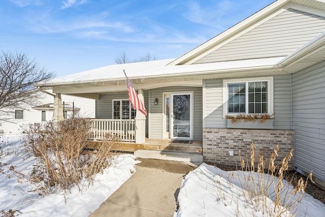 snow covered property entrance with covered porch