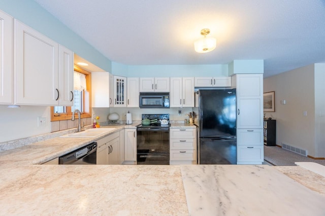 kitchen featuring white cabinetry, sink, black appliances, and light stone countertops