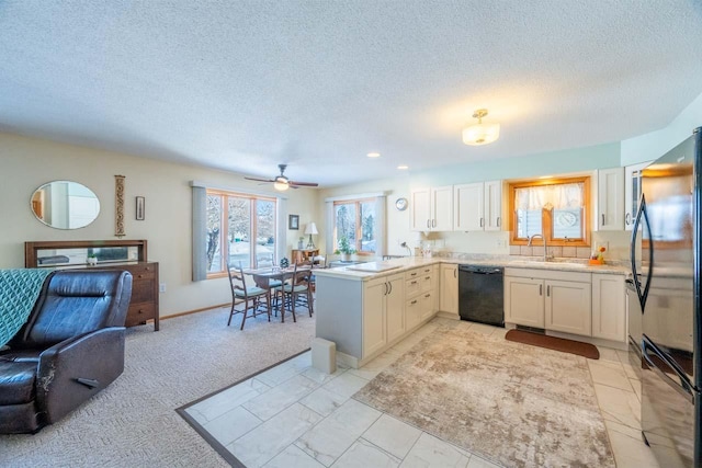 kitchen featuring white cabinetry, black dishwasher, sink, fridge, and kitchen peninsula