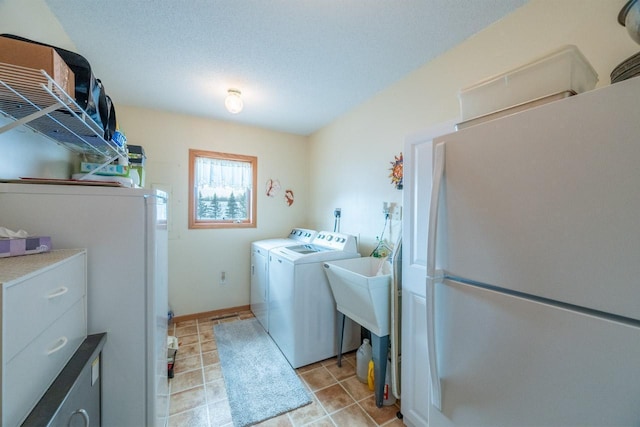 clothes washing area with light tile patterned flooring, washing machine and dryer, and a textured ceiling