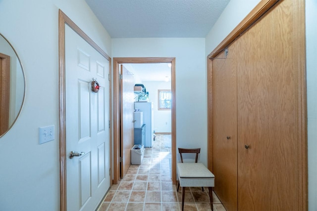 hallway with a textured ceiling and light tile patterned floors