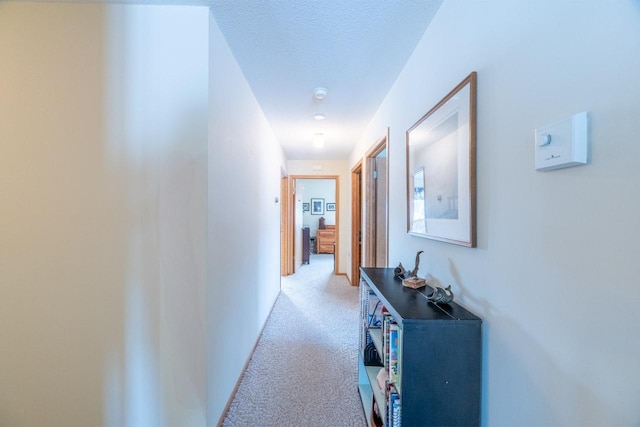 corridor with light colored carpet and a textured ceiling