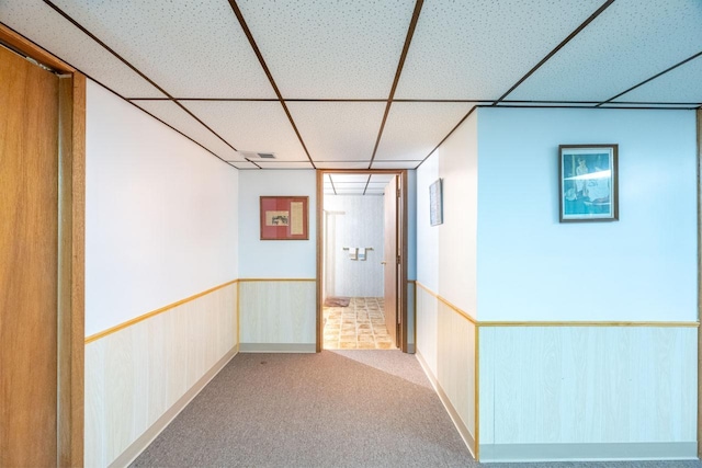 hallway featuring a paneled ceiling and light carpet