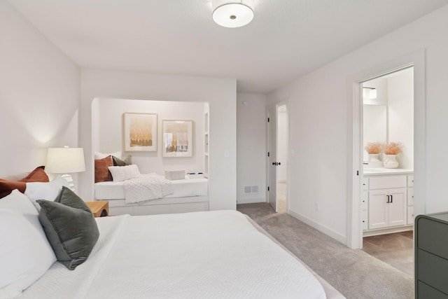 bedroom with connected bathroom and light colored carpet