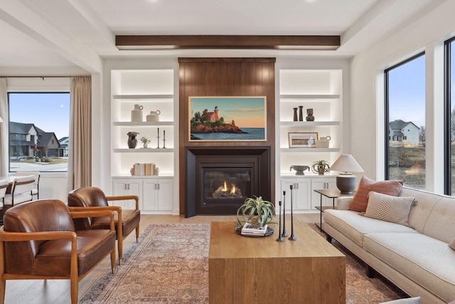 living room featuring light hardwood / wood-style flooring, a fireplace, and built in features