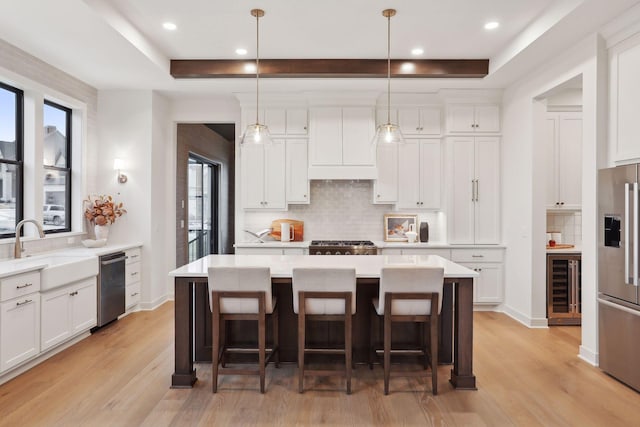 kitchen with pendant lighting, appliances with stainless steel finishes, a center island, and sink