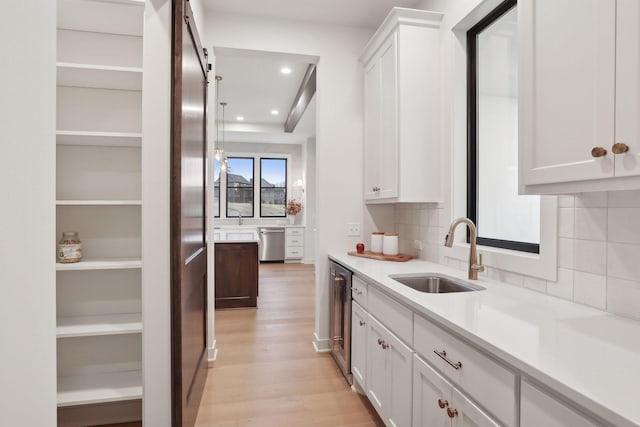 kitchen featuring sink, wine cooler, white cabinets, stainless steel appliances, and light wood-type flooring