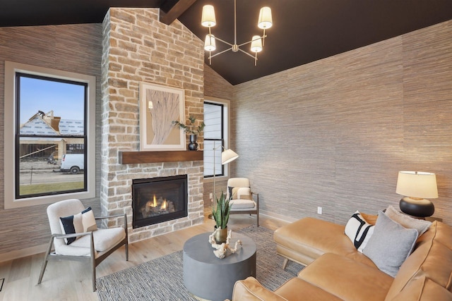 living room with an outdoor stone fireplace, hardwood / wood-style floors, high vaulted ceiling, a chandelier, and beamed ceiling